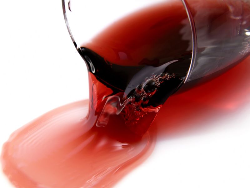 Rotwein läuft aus umgefallenen Weinglas